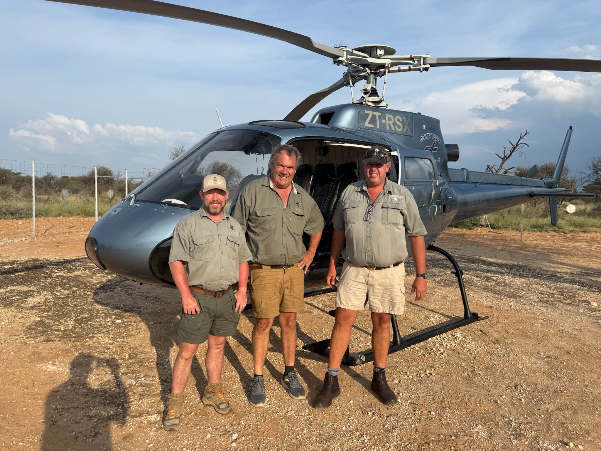 Professional hunters beside a helicopter at camp