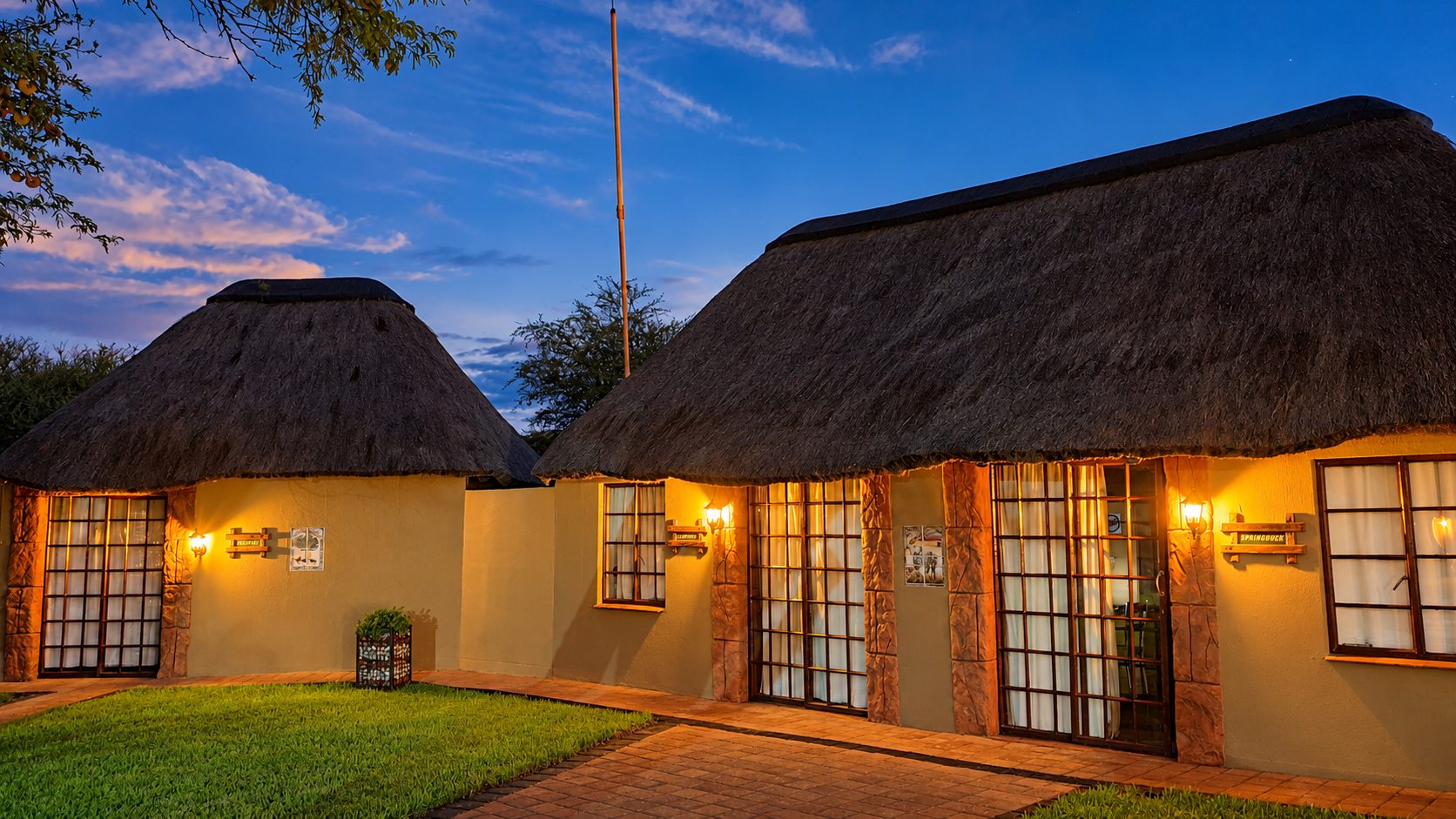 Thatched lodge chalets lit at dusk