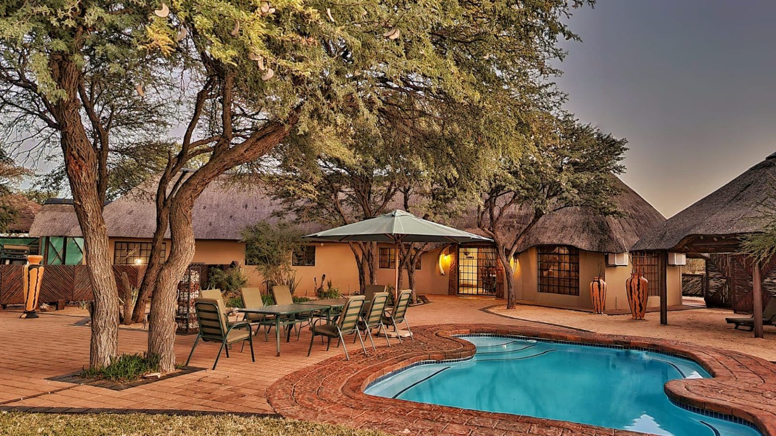 Mankwe Kalahari Lodge pool and thatched chalets